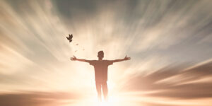 A man with outstretched arms with doves flying in front of him