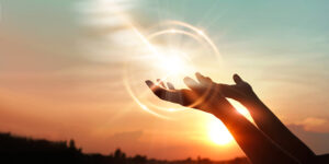 Two hands upright with the rising sun in the background