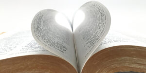 A bible with two pages bending towards the spine forming a heart shape