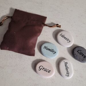 Five stones that say Humility, Identity, Love, Authority, and Grace with a brown pouch.