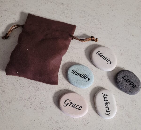 Five stones that say Humility, Identity, Love, Authority, and Grace with a brown pouch.