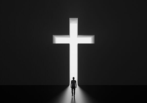 A silhouette of a man standing in front of an illuminated white cross
