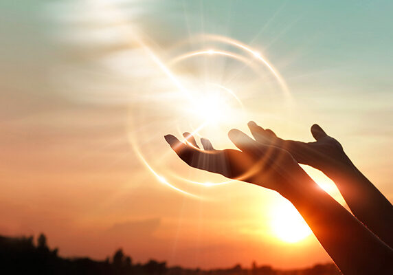 Two hands upright with the rising sun in the background