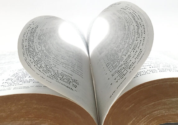 A bible with two pages bending towards the spine forming a heart shape